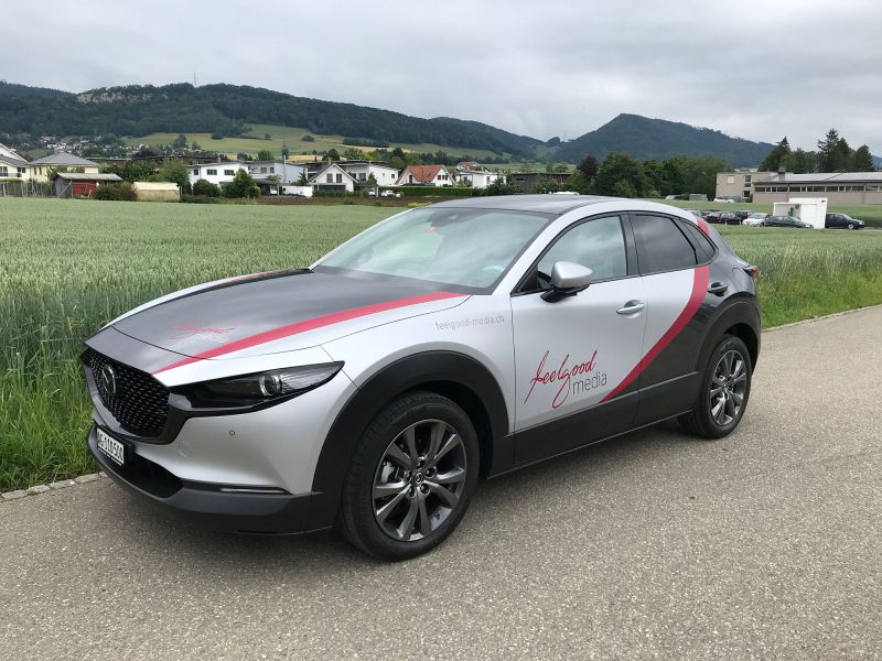 Mazda in Silber und Schwarz mit roter Beschriftung feelgood Media.