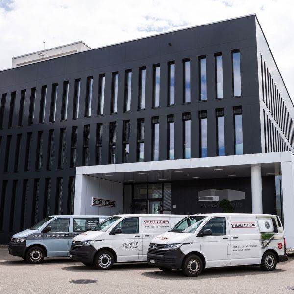 Transportbusse Stiebel Eltron mit seitlicher Beschriftung vor Bürogebäude.