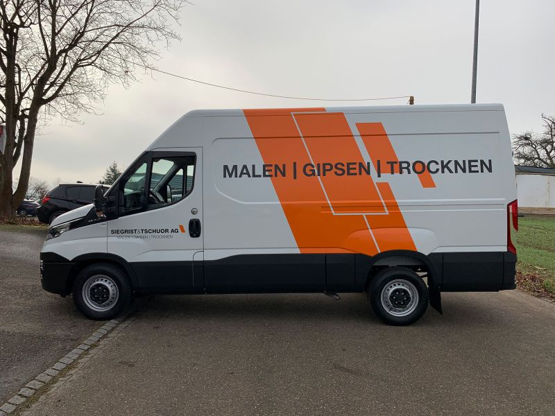 Transportbus weiss mit seitlicher Aufschrift Siegrist & Tschuor AG, mit orangen Streifen.