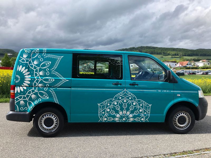 Transportbus in türkis mit seitlicher Beschriftung Blumenmotiv weiss.