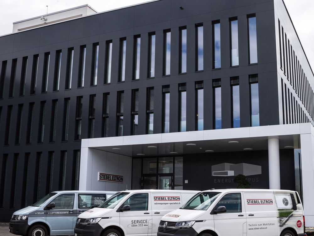 Transportbusse Stiebel Eltron mit seitlicher Beschriftung vor Bürogebäude.